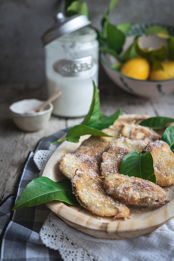 Von oben Teller mit Paparajotes, einem typischen Dessert aus Murcia in Spanien, hergestellt aus Zitronenblättern und bestreut mit Zucker auf einem rustikalen Holztisch