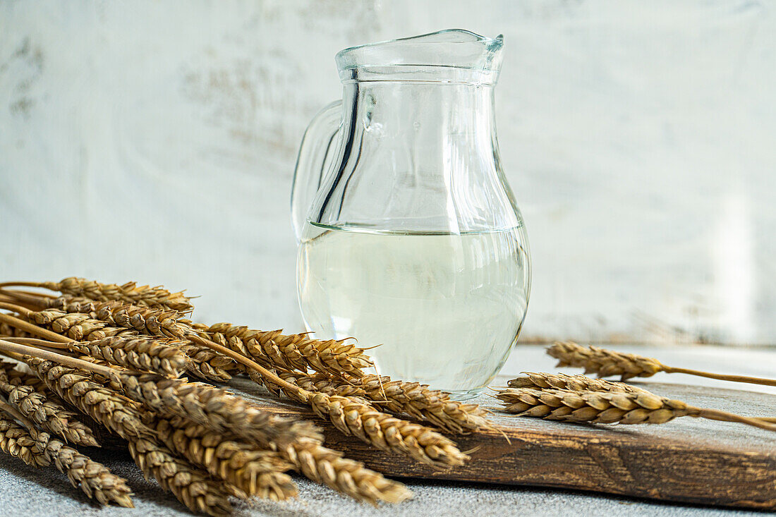 Traditional Ukrainian alcoholic drink made from wheat and known as Gorilka served in transparent jar placed on cutting board against blurred background