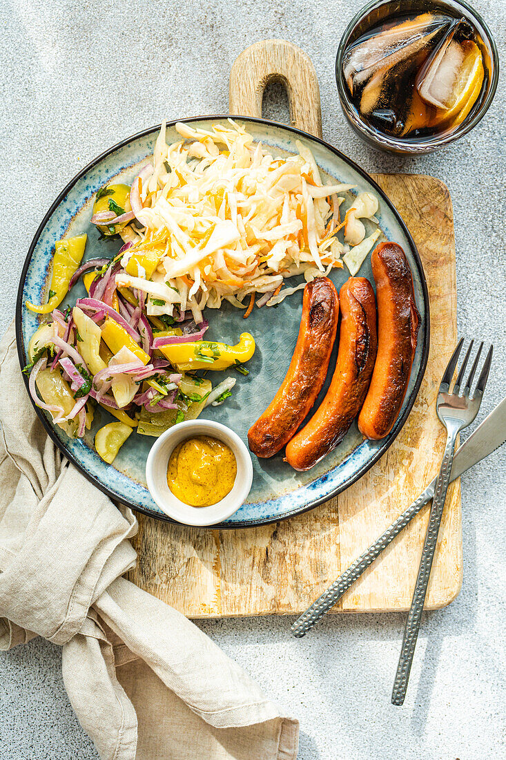 Vegetables and sausages on plate served with glass of cola drink