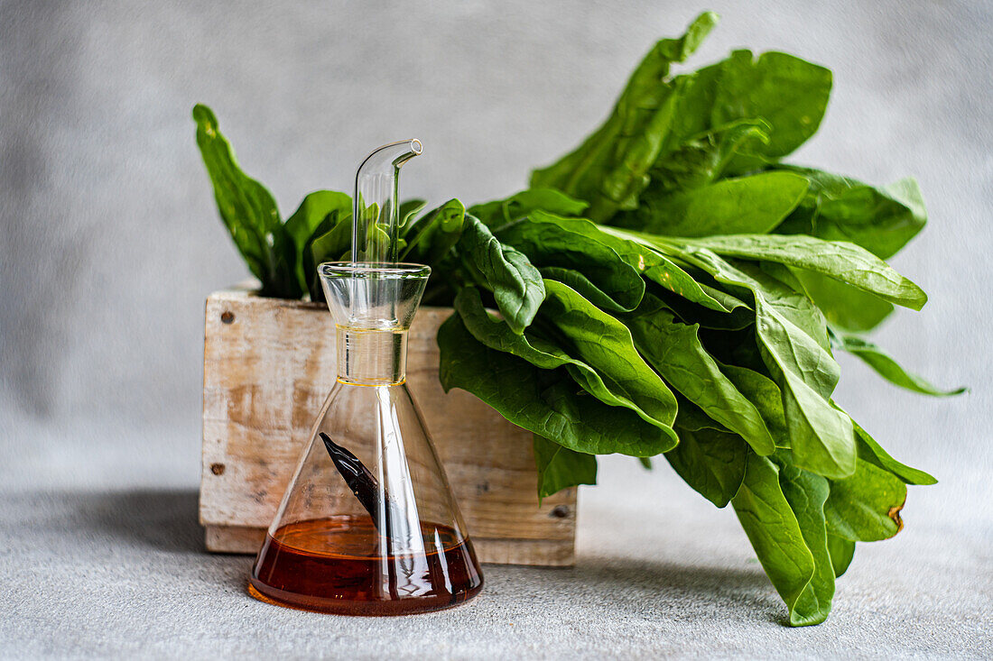 Vibrant spinach leaves in a rustic wooden box paired with a sleek glass decanter of olive oil symbolizing fresh salad ingredients and preparation