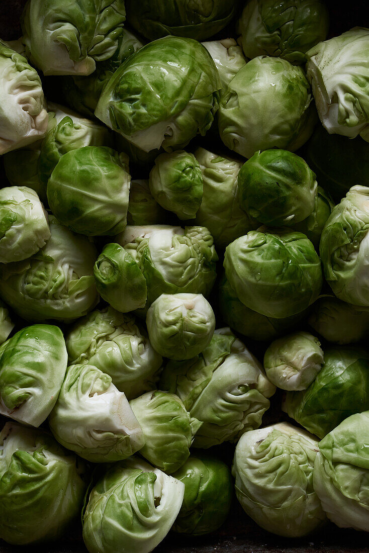 Close-up of fresh, green brussels sprouts piled together showcasing their textures and natural patterns