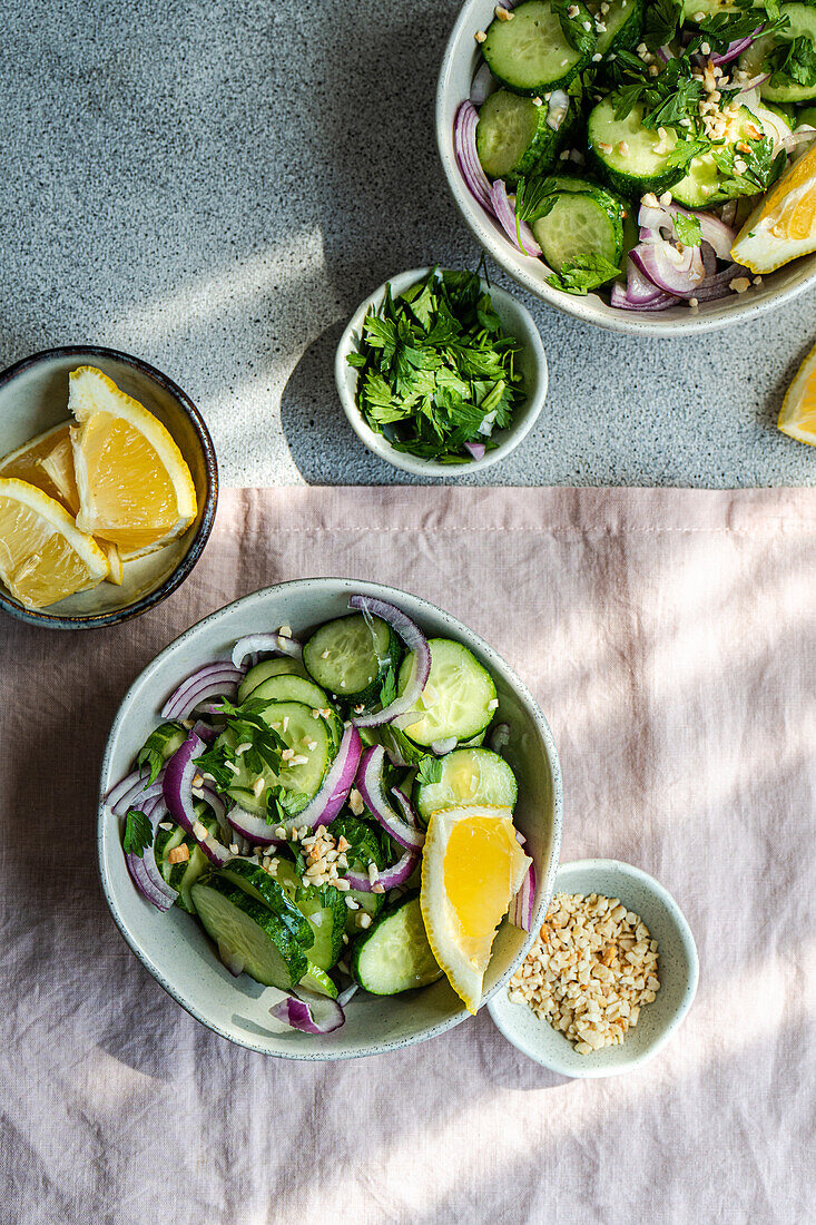 From above of healthy vegetables salads with organic cucumber, red onion, coriander and chopped nuts placed in a concrete table