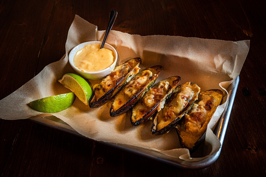 Baked shellfish mussels with cheese sauce served with lime slice