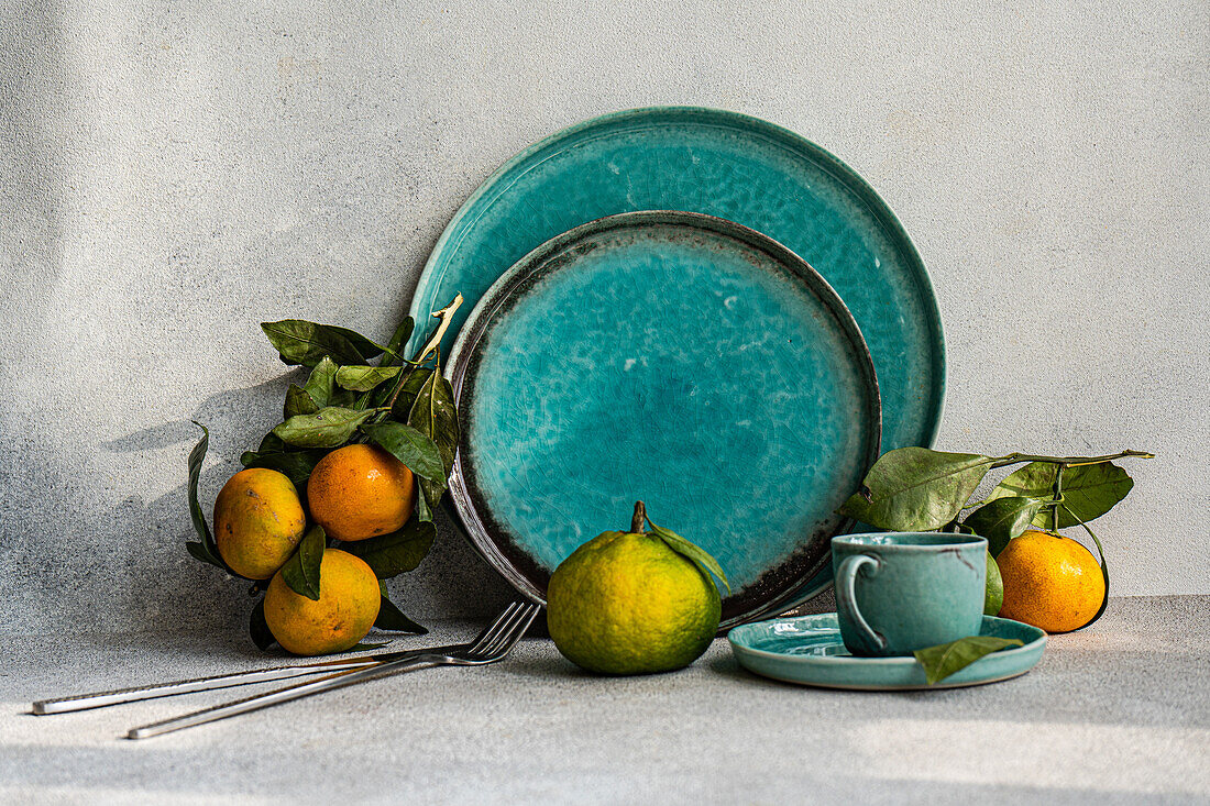 A beautifully arranged table setting in turquoise tones, complemented by fresh citrus fruits, creating an inviting dining atmosphere.