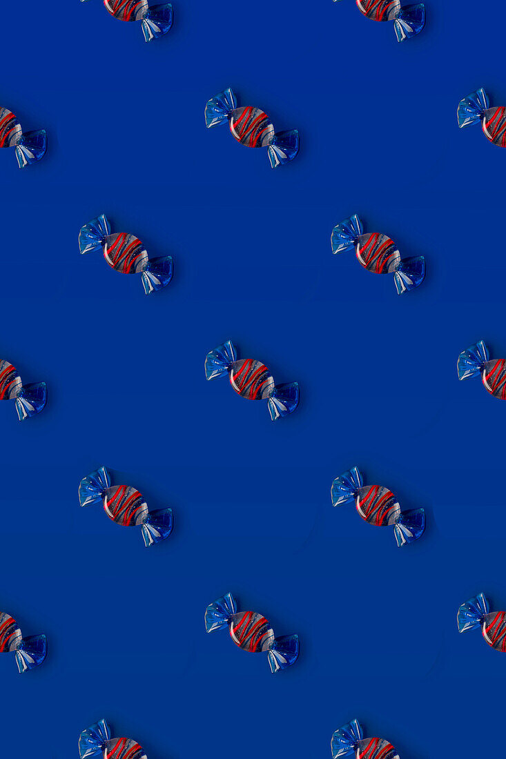 Draufsicht auf ein Muster aus ganzen süßen Kristallbonbons auf blauem Hintergrund