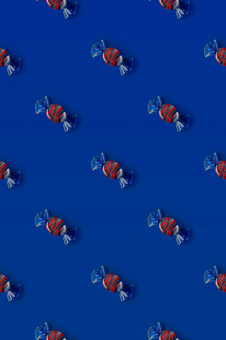 Top view of pattern of whole sweet crystal candies arranged on blue background