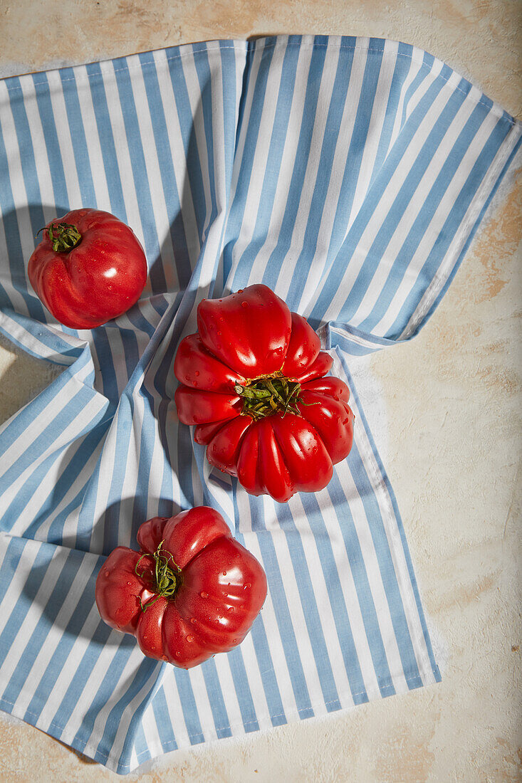 Von oben reife frische rote Tomaten auf rauem kariertem Tischtuch auf ebener Tischfläche in Innenräumen