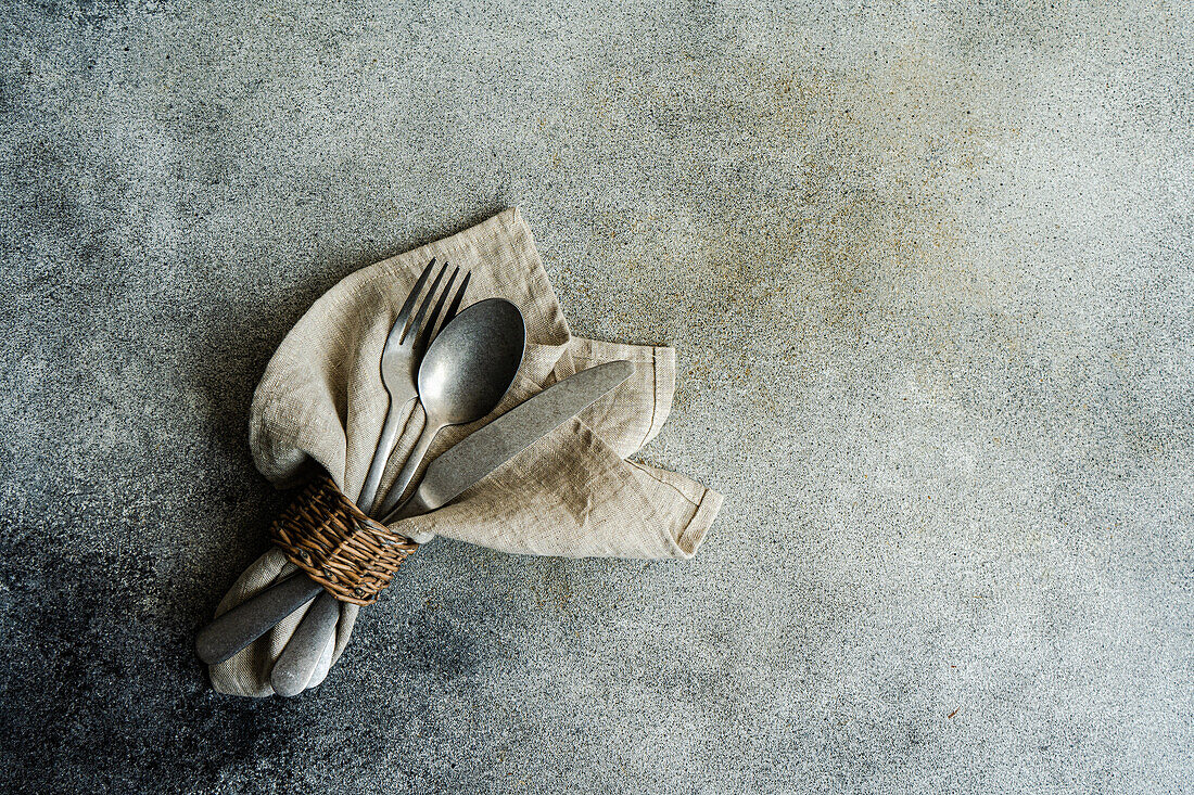 Top view of vintage cutlery set with napkin spoon knife and fork on gray surface in daylight