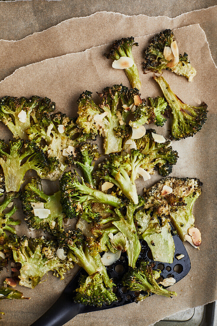 From above baked cooked green broccoli stems with cheese and pepper placed on wooden background