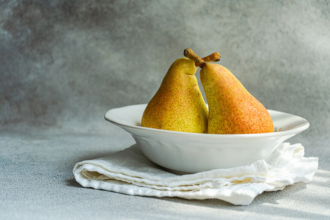 White marble plate with fresh juicy pears placed on a concrete table