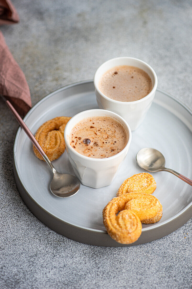 Tasse Kaffee mit Milch und Keksen auf dem Teller auf dem Betontisch serviert
