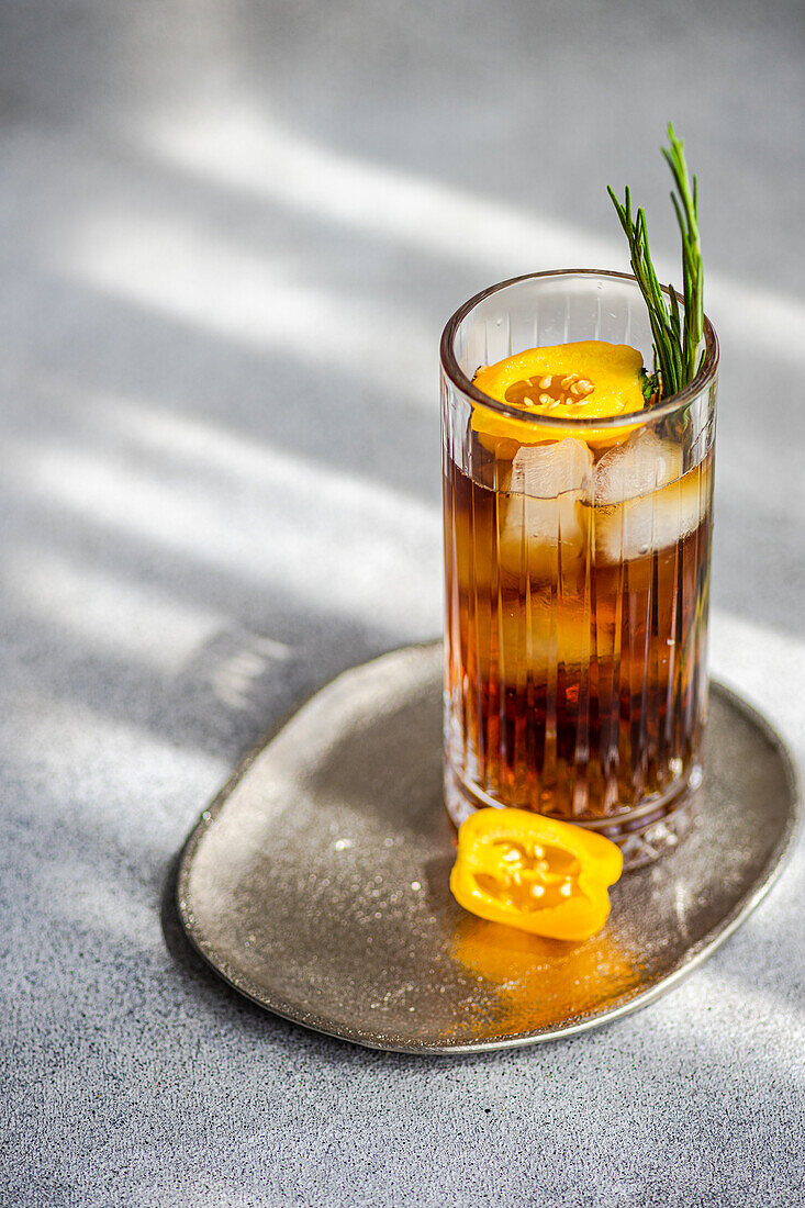 High angle of spicy Margarita cocktail served with ice cubes and sliced of fresh fruit placed on tray against gray background