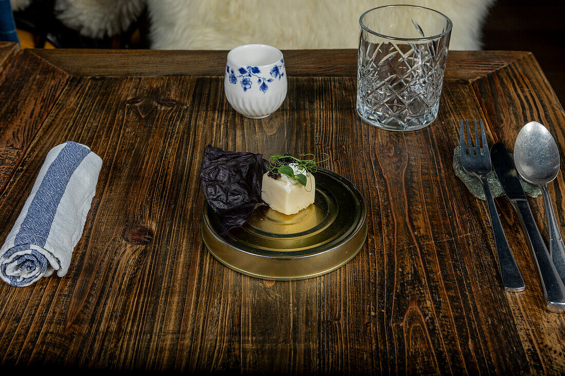 Ein Gericht aus der Fusionsküche, serviert in einem Michelin-Stern-Restaurant in Zermatt, mit lokalen und saisonalen Produkten, elegant präsentiert auf einem Holztisch