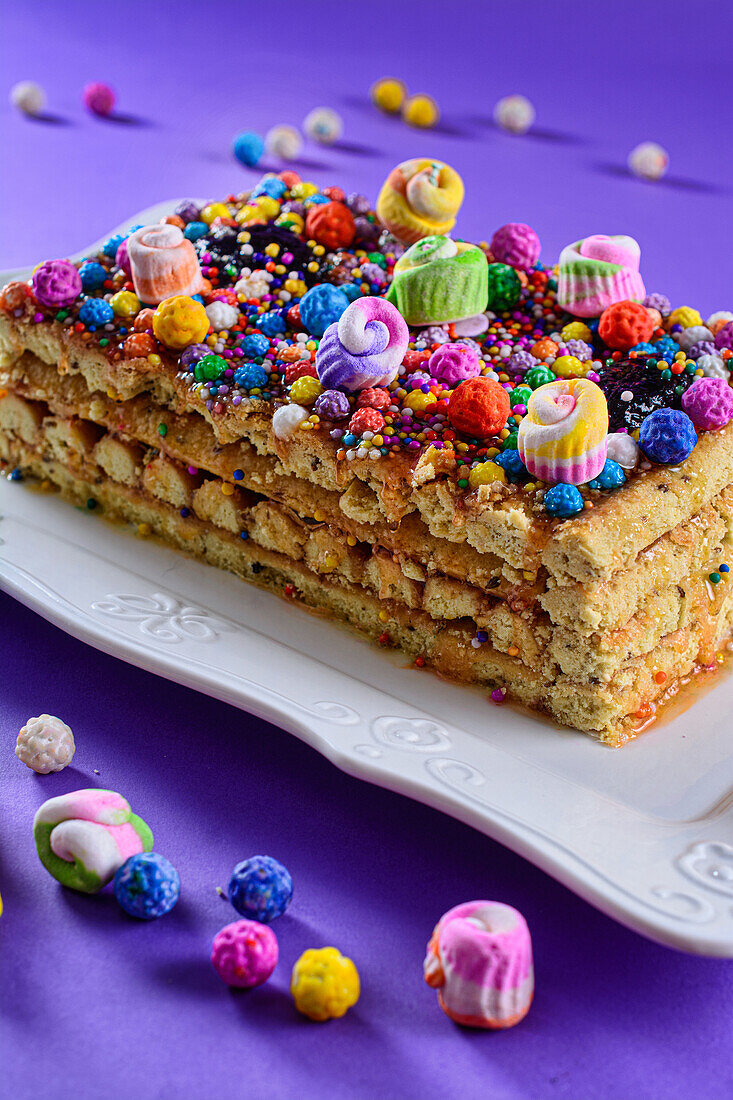 Delicious homemade Peruvian nougat decorated with colorful curly icing sugar cream served on white tray over purple background