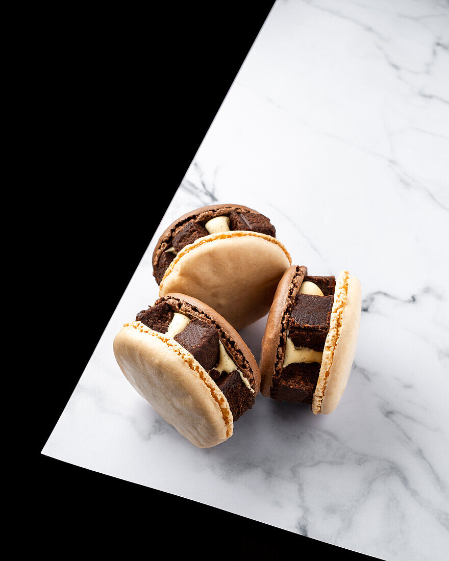 Top view of chocolate brownie tasty macaroons against marble table and black background