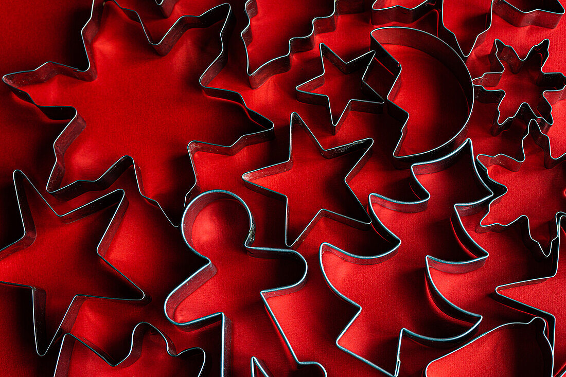 Top view of set of various cookie cutters located on red surface as symbol for Christmas holiday