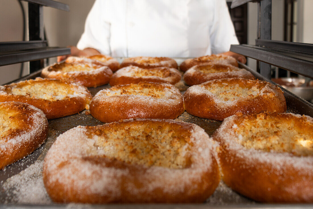 Anonymer Bäcker in weißer Uniform steht an der Theke und bereitet leckeres Brot mit Käse in einer Bäckerei zu