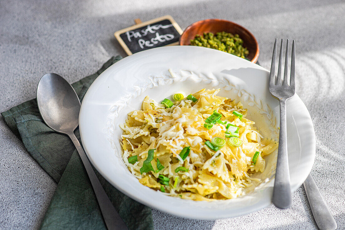 Ein köstlicher Teller Farfalle-Nudeln mit frischer Pesto-Sauce, serviert auf einem sauberen weißen Tischtuch, perfekt für kulinarische Themen