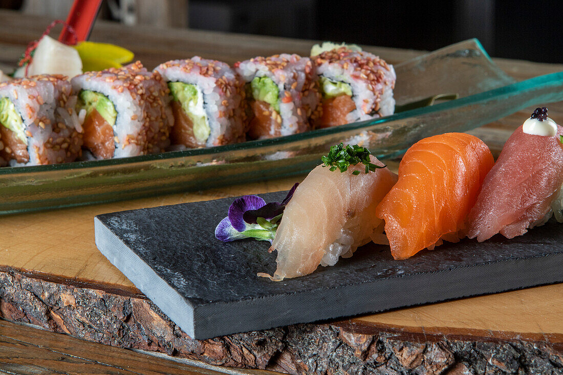 From above of delicious uramaki sushi and nigiri sushi together with sashimi in small bowls on wooden background