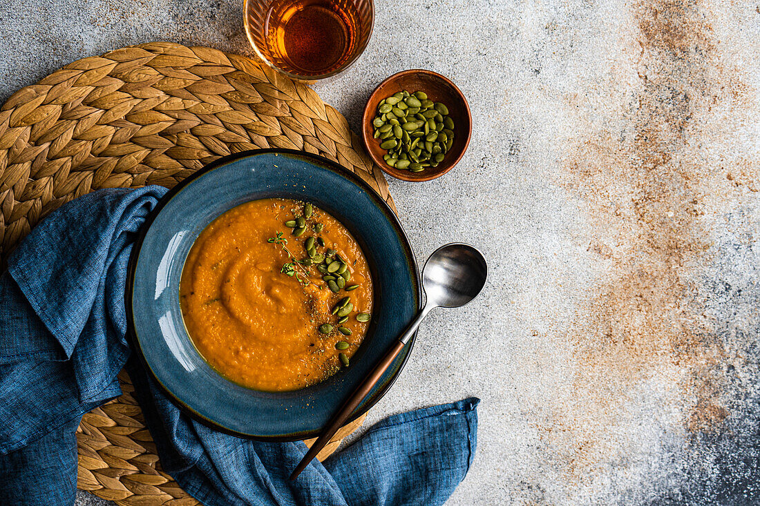 Tasty pumpkin cream soup with organic herbs and seeds in blue vintage ceramic bowl