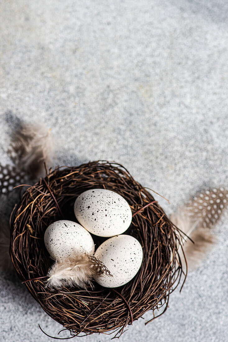 Von oben Nest mit Heu und Eiern auf Betonhintergrund als Osterkartenkonzept