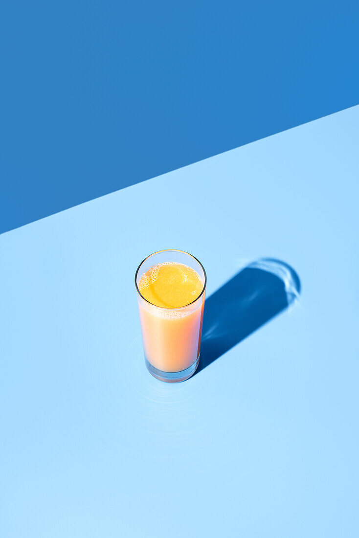 Blick von oben auf gepressten Orangensaft auf blauem Hintergrund