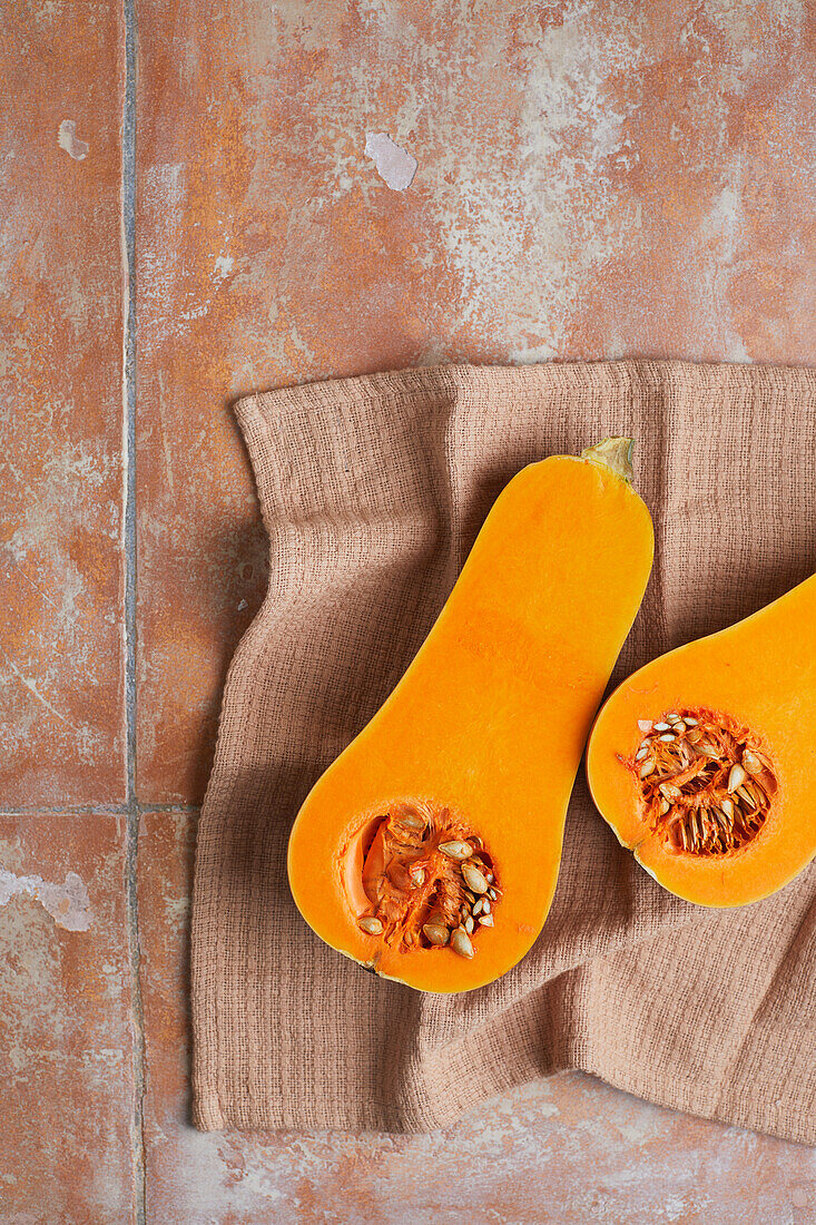 From above of juicy pumpkin split in half orange with seeds and flesh placed on table