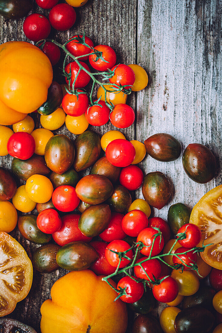 Bright background of various fresh colorful tomatoes placed on wooden table during harvest season
