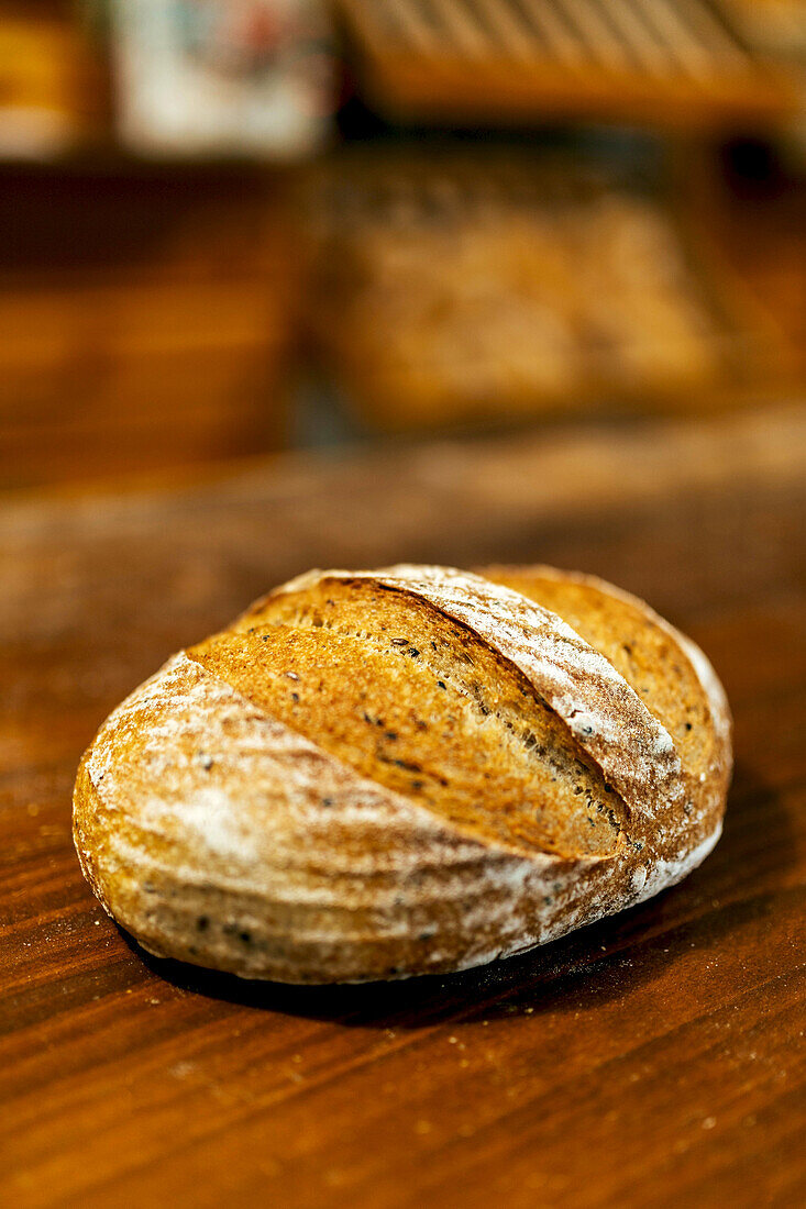Closeup of freshly baked tasty loaf of bread with crispy crust placed on wooden table in kitchen at bakehouse