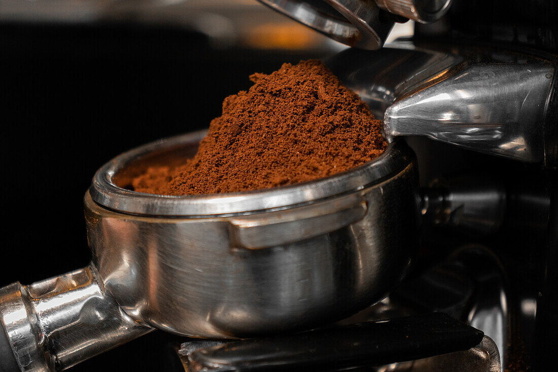 Fresh ground coffee in portafilter of professional grinder in cafe