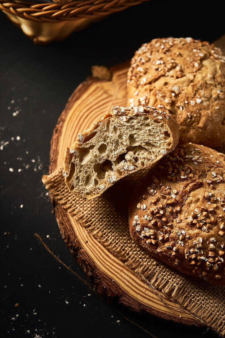 High angle of delicious freshly baked bread with crispy crust sprinkled with mix of seeds and placed on wooden cutting board