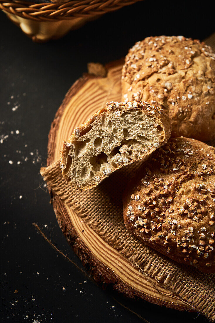 Hoher Blickwinkel auf köstliches, frisch gebackenes Brot mit knuspriger Kruste, bestreut mit einer Mischung aus Samen und auf einem Holzbrett platziert