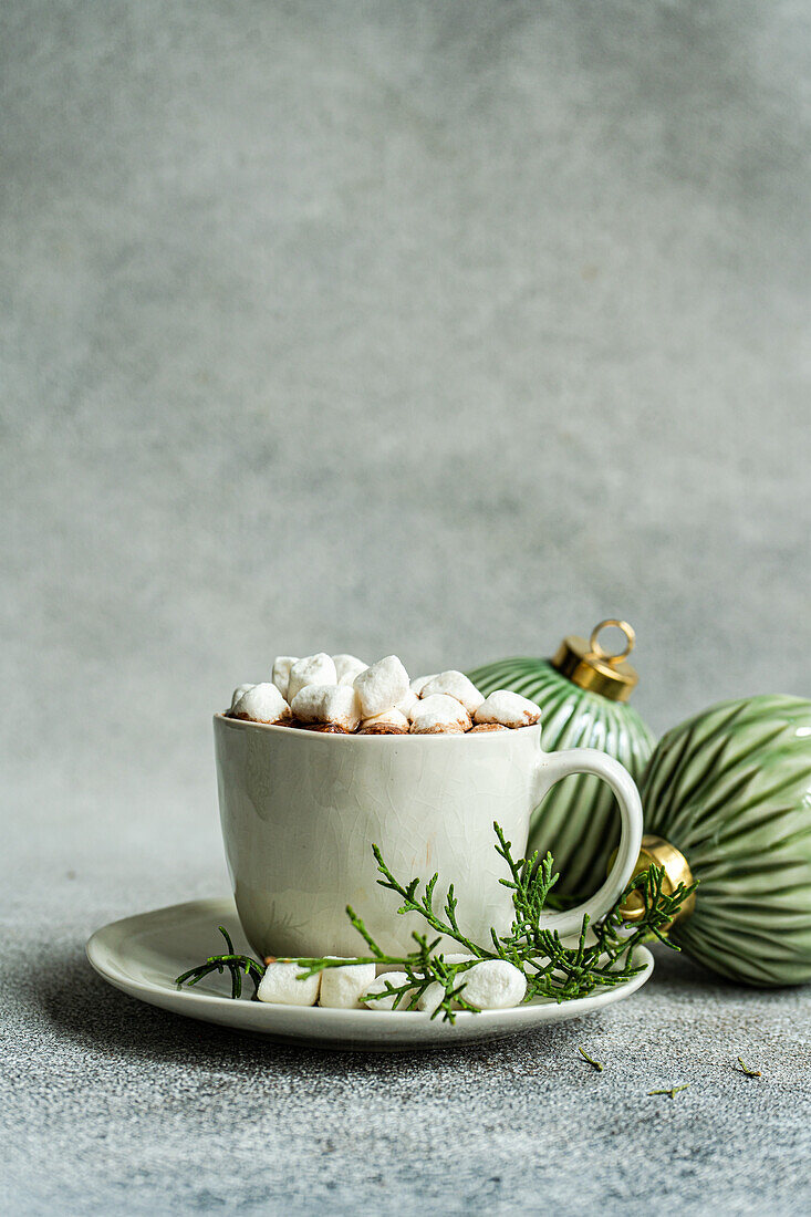 Delicious cocoa with marshmallow on plate with fir twigs placed near Christmas balls