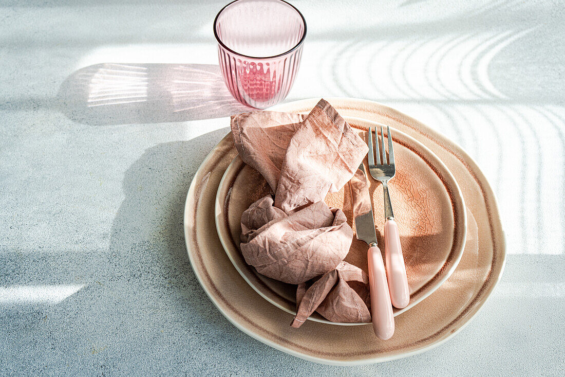 An elegant Easter table setting featuring pastel-colored plates, a pink napkin, and coordinated cutlery, with soft lighting casting a serene ambiance.