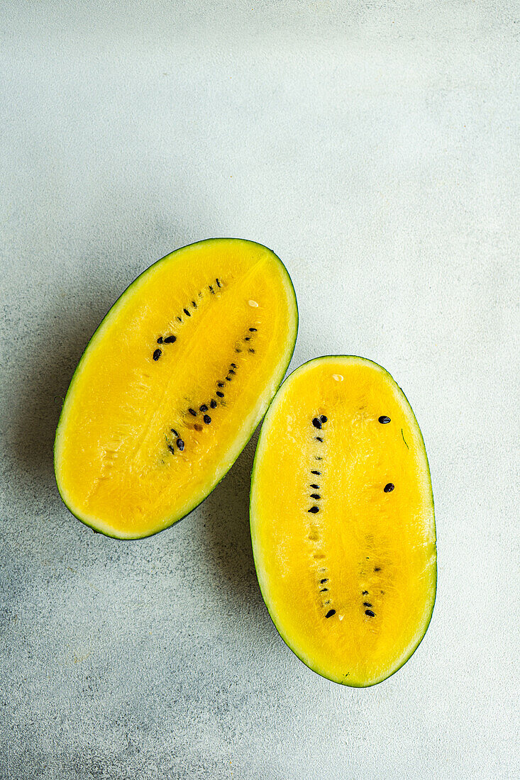 Draufsicht auf Scheiben einer gelben Bio-Wassermelone auf einer grauen Fläche