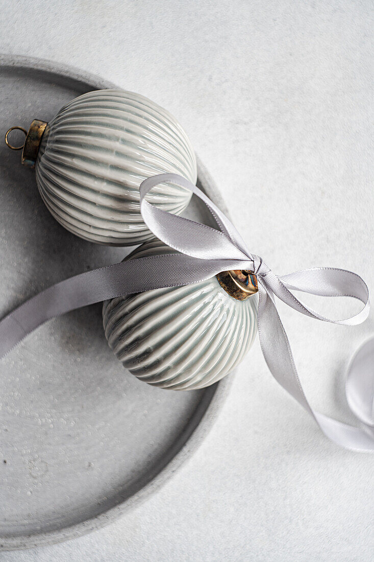 Crop top view of balls decorated with satin ribbon as symbol of Christmas time placed on gray surface
