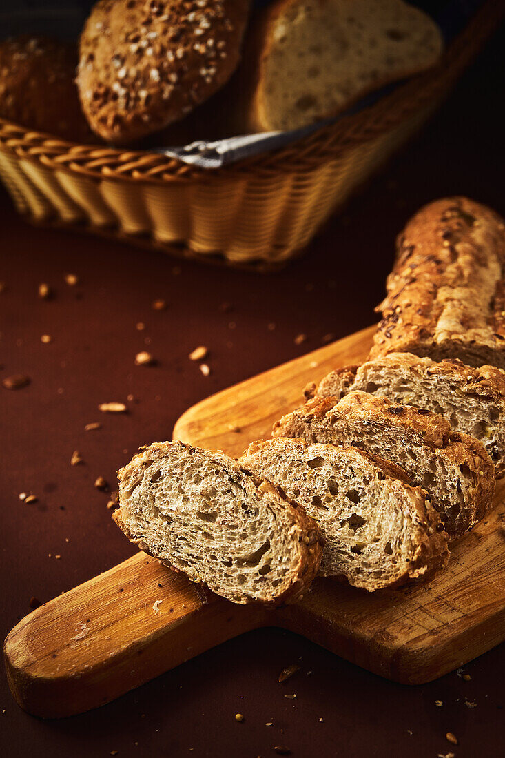 High angle of delicious freshly baked bread with crispy crust sprinkled with mix of seeds and placed on wooden cutting board