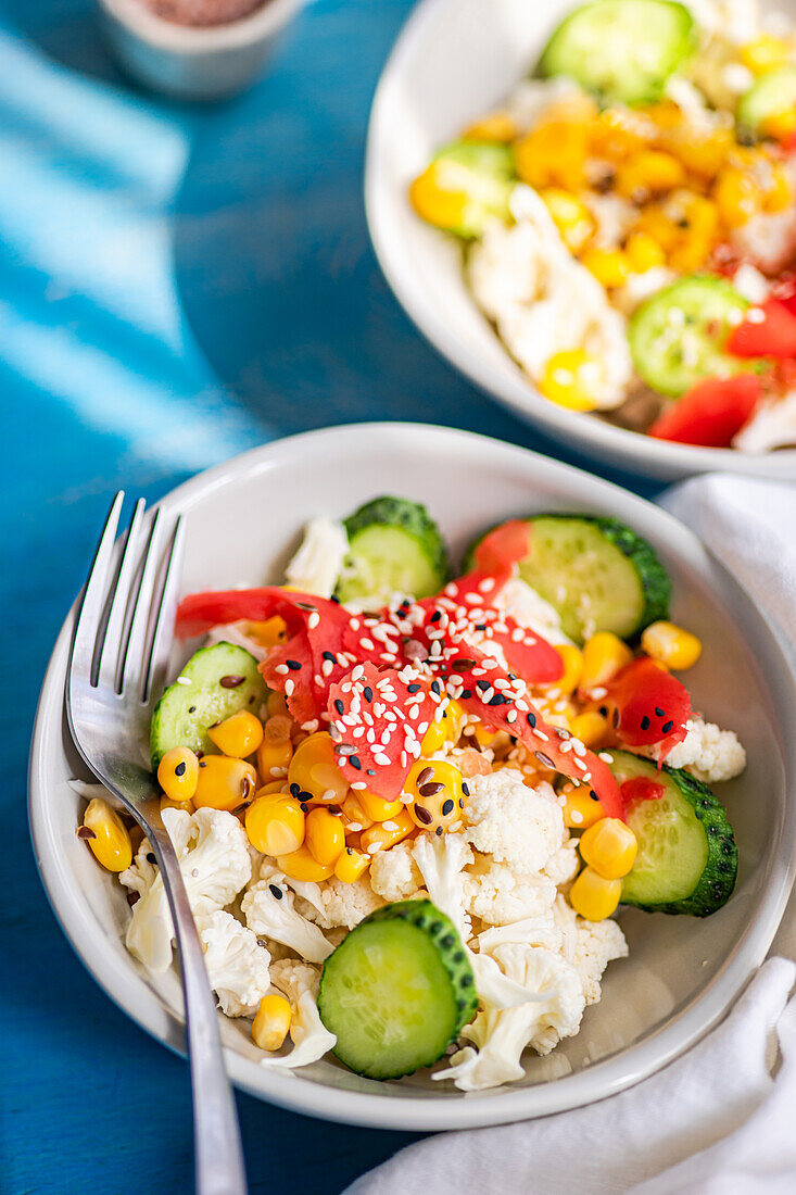 Top view healthy salads with assorted vegetables greens served in bowl with fork on a table with a blue background