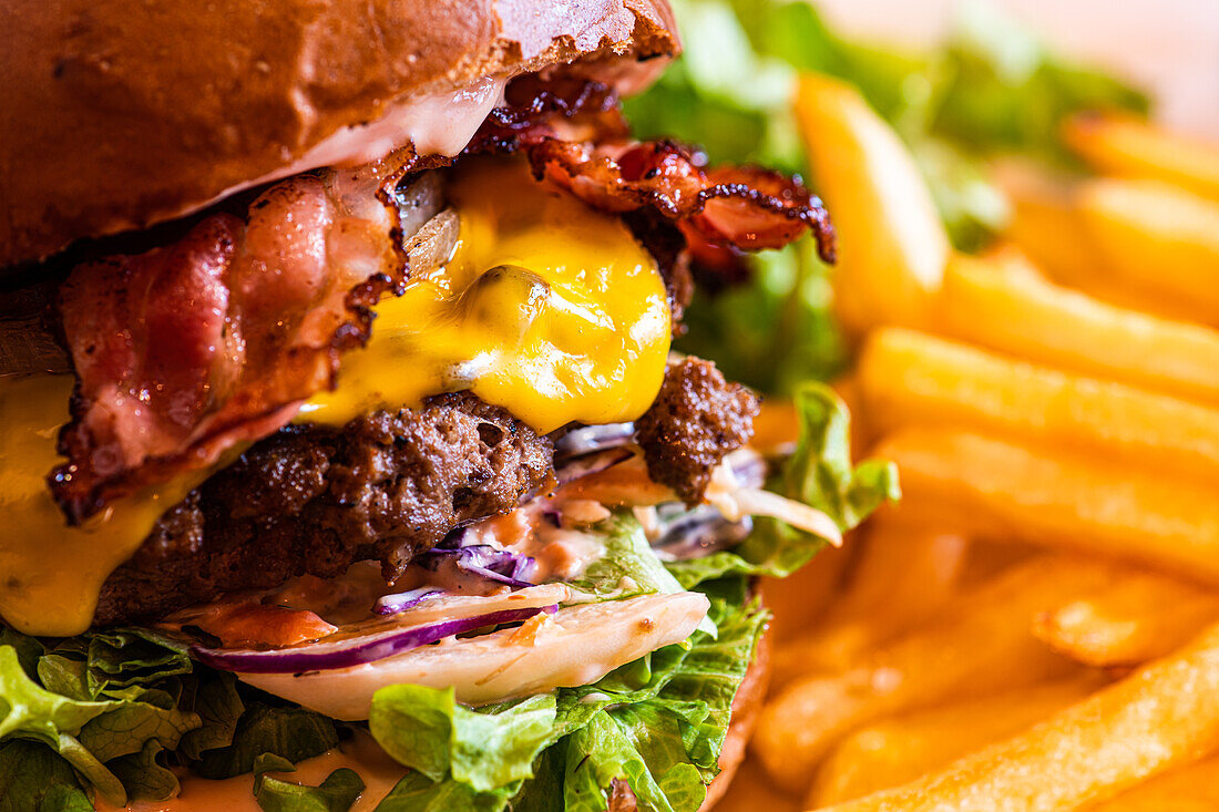 Hausgemachter Cheeseburger mit Käse und Gemüse, serviert mit Pommes frites und Salat