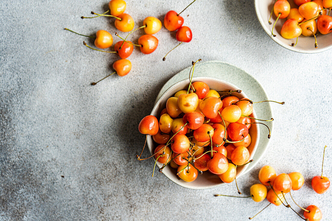 Bowl with organic ripe white sweet cherries on the concrete kitchen table