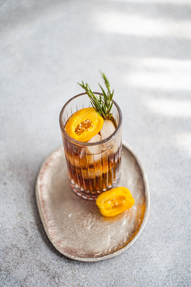 Hoher Blickwinkel auf einen würzigen Margarita-Cocktail mit Eiswürfeln und frischen Fruchtscheiben auf einem Tablett vor grauem Hintergrund