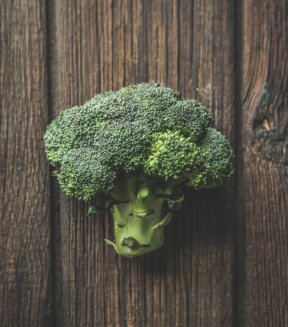 Close up of whole green broccoli at brown rustic wooden background. Organic vegetable. Healthy lifestyle. Top view.