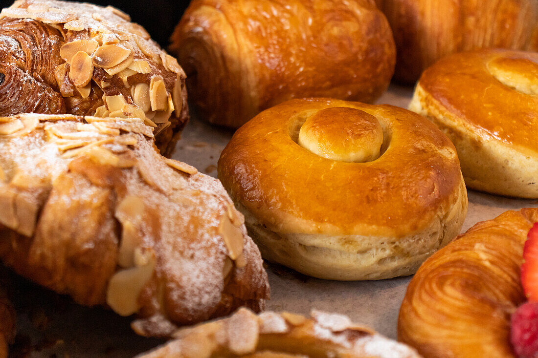 High angle closeup of assorted baked pastries with croissants and cakes placed on table in bakery
