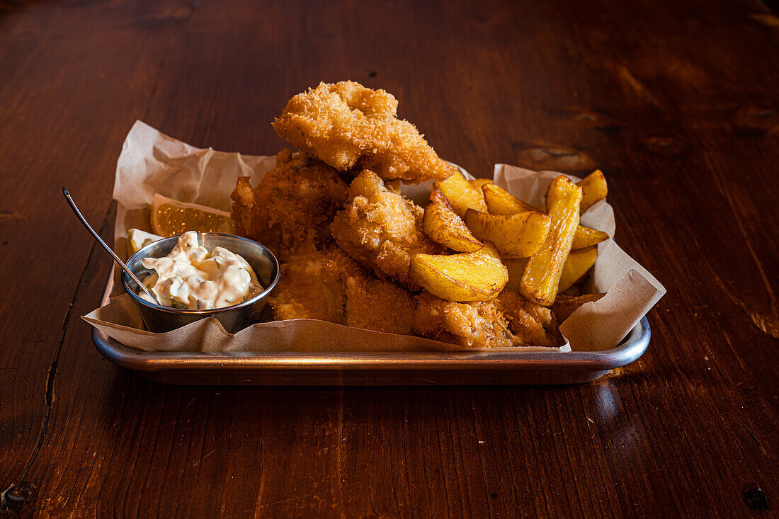 Traditional English dish Fish and chips served with french fries on wooden table