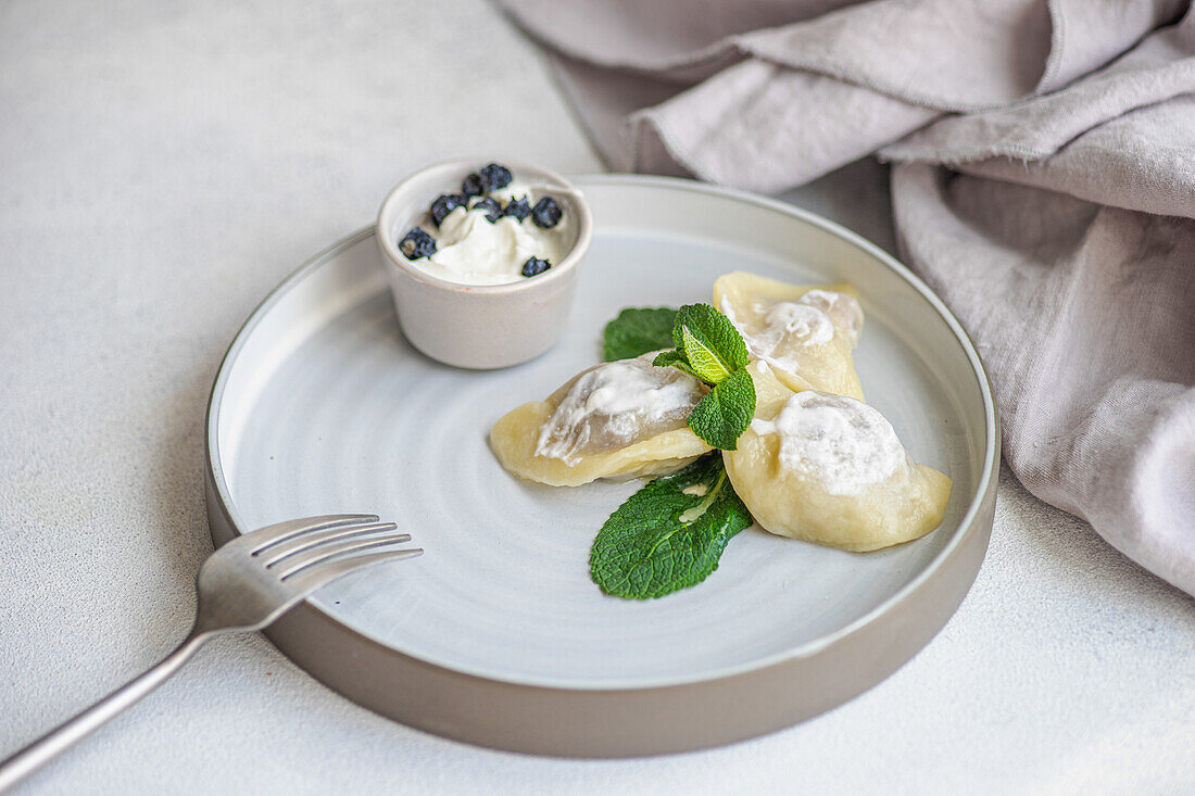 From above tasty traditional Ukrainian dumplings with cherry and sour cream with mint