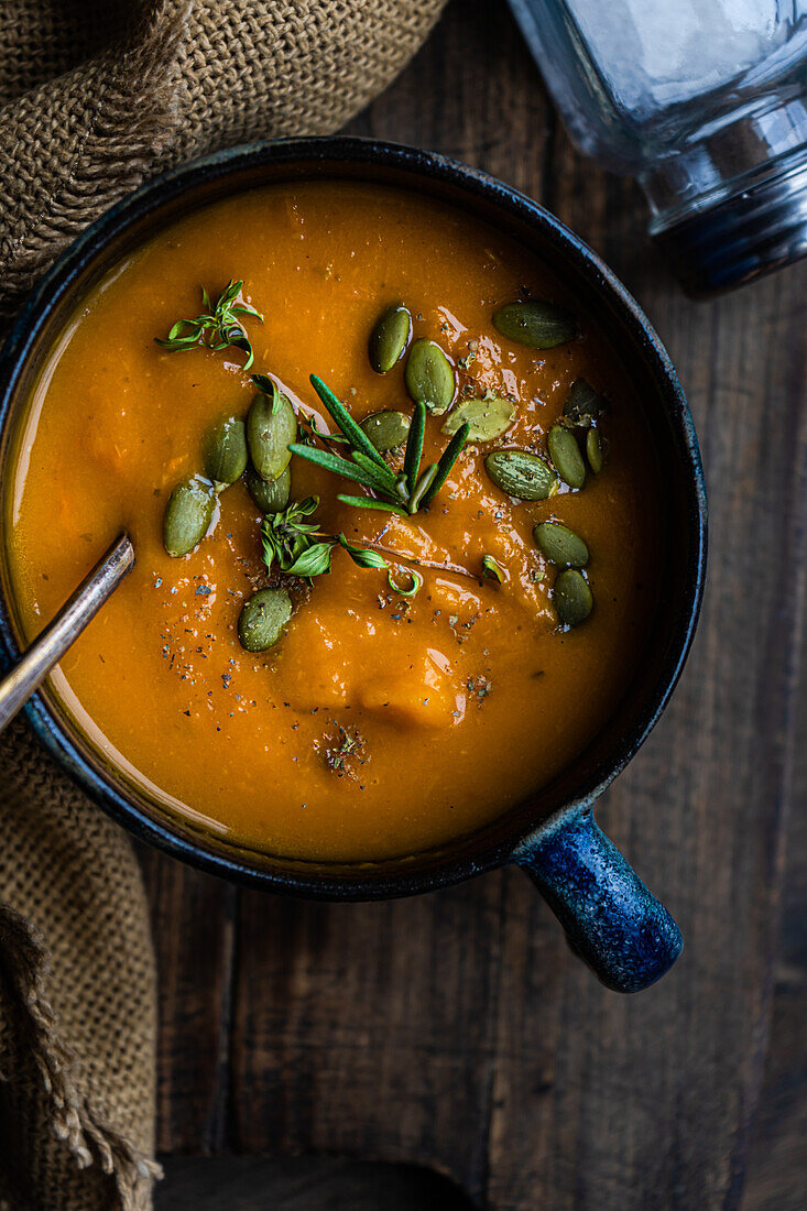 Leckere Kürbiscremesuppe mit Bio-Kräutern und Samen in blauer Vintage-Keramikschale