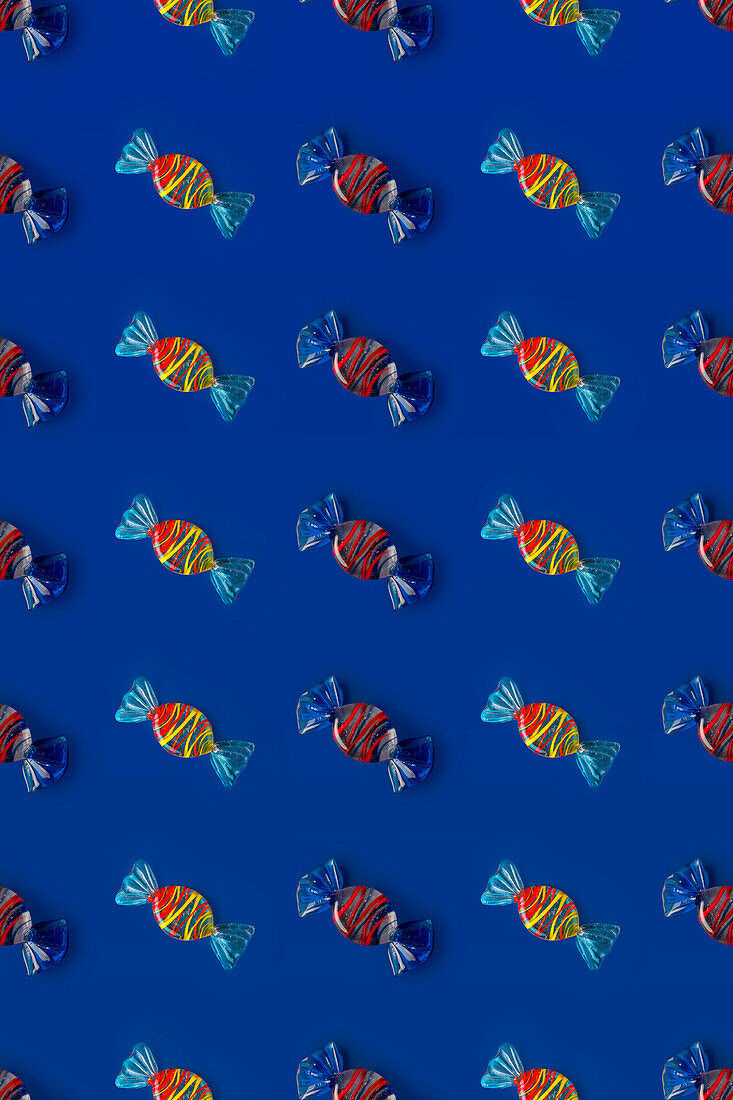 Draufsicht auf ein Muster aus ganzen süßen Kristallbonbons auf blauem Hintergrund