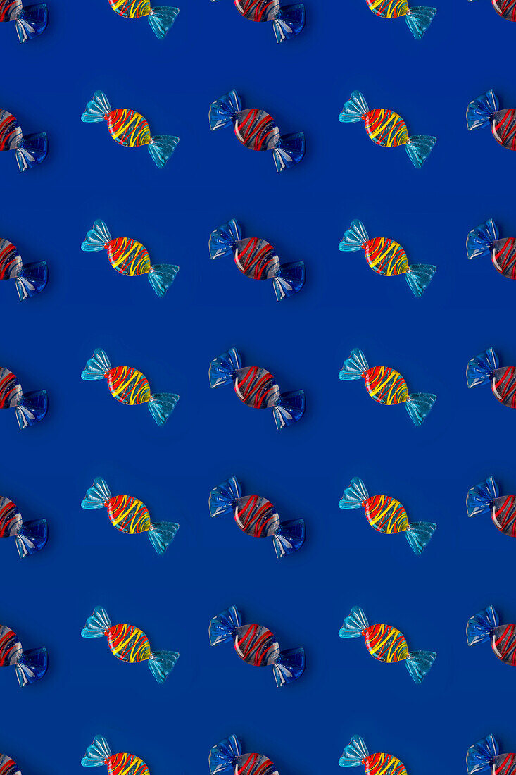 Top view of pattern of whole sweet crystal candies arranged on blue background