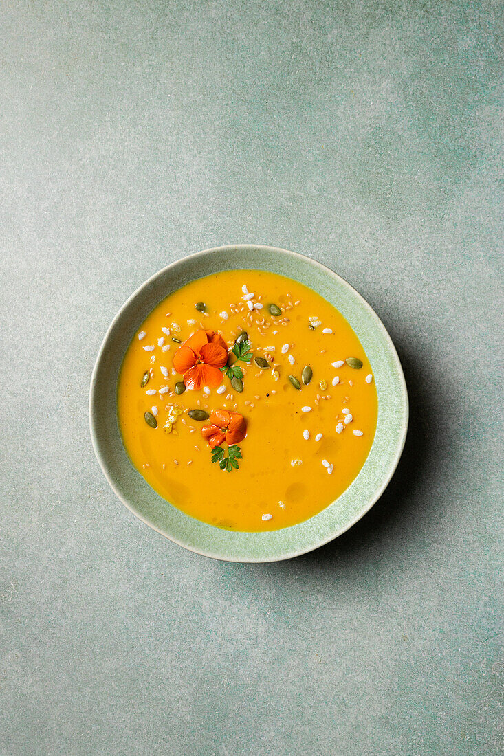 Top view of appetizing vegetarian pumpkin cream soup with herbs and sesame seeds served in bowls on table