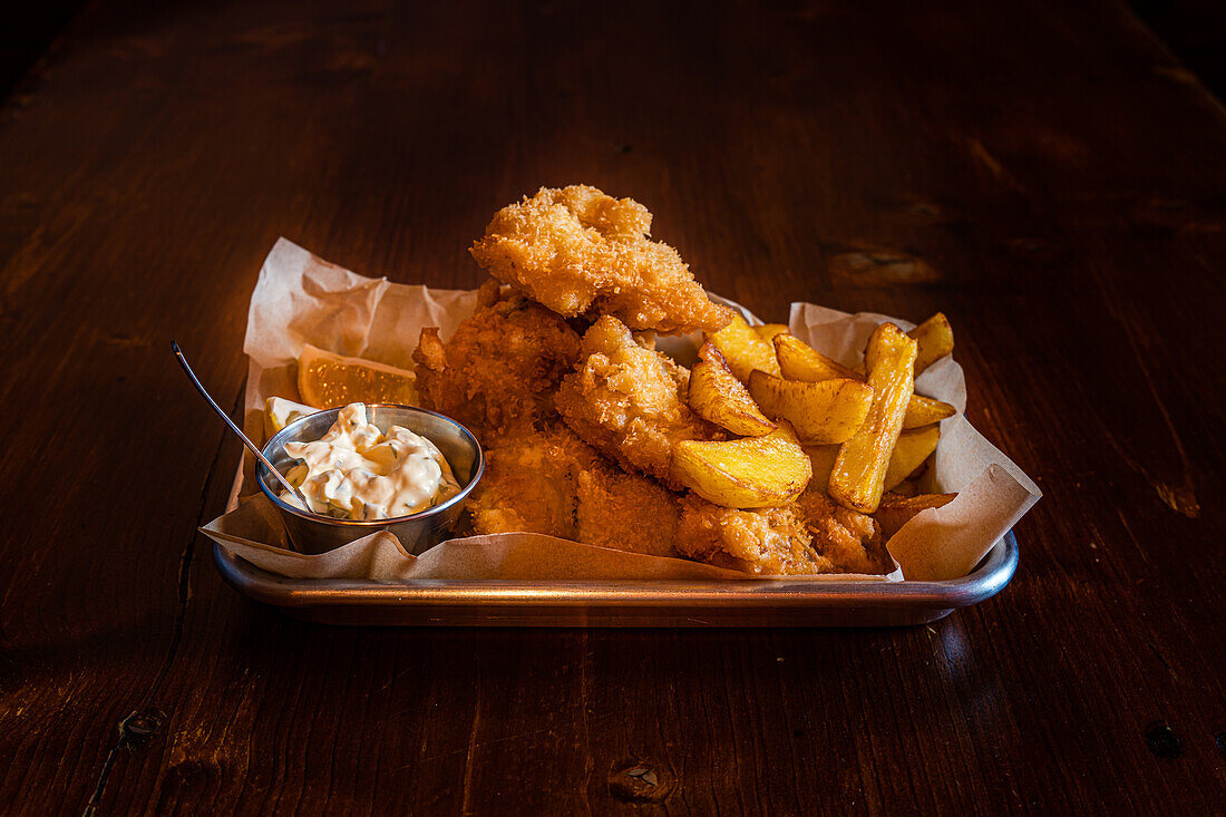Traditional English dish Fish and chips served with french fries on wooden table